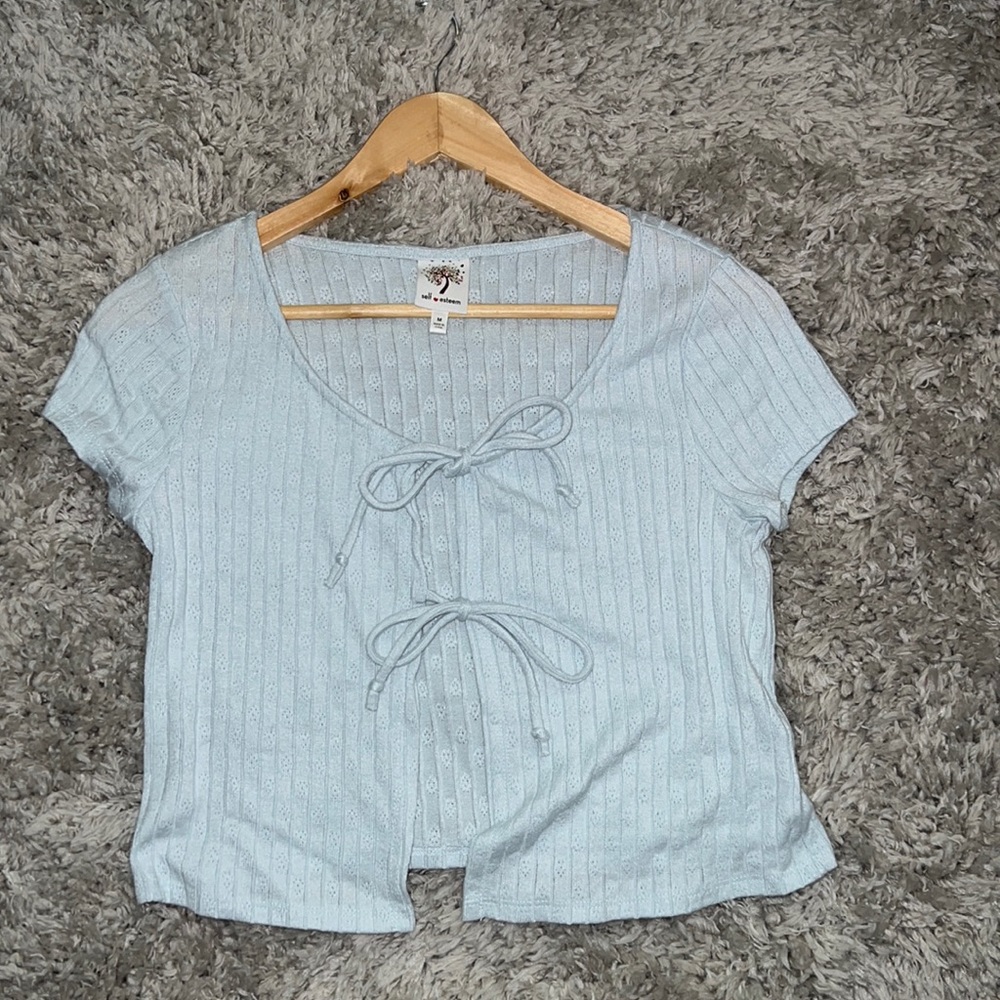 A cute double tie shirt in the front, size medium, color is a light baby blue.